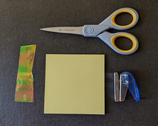 Iridescent cellophane, sticky note, scissors, and hole punch